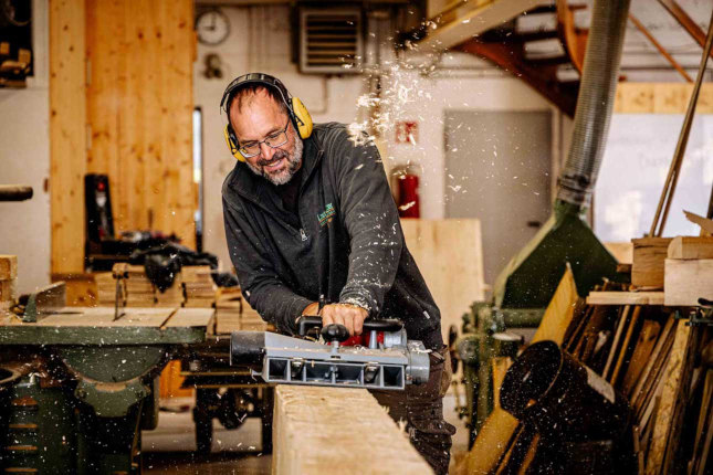 Ansicht: Mitarbeiter beim Abhobeln eines Balkens